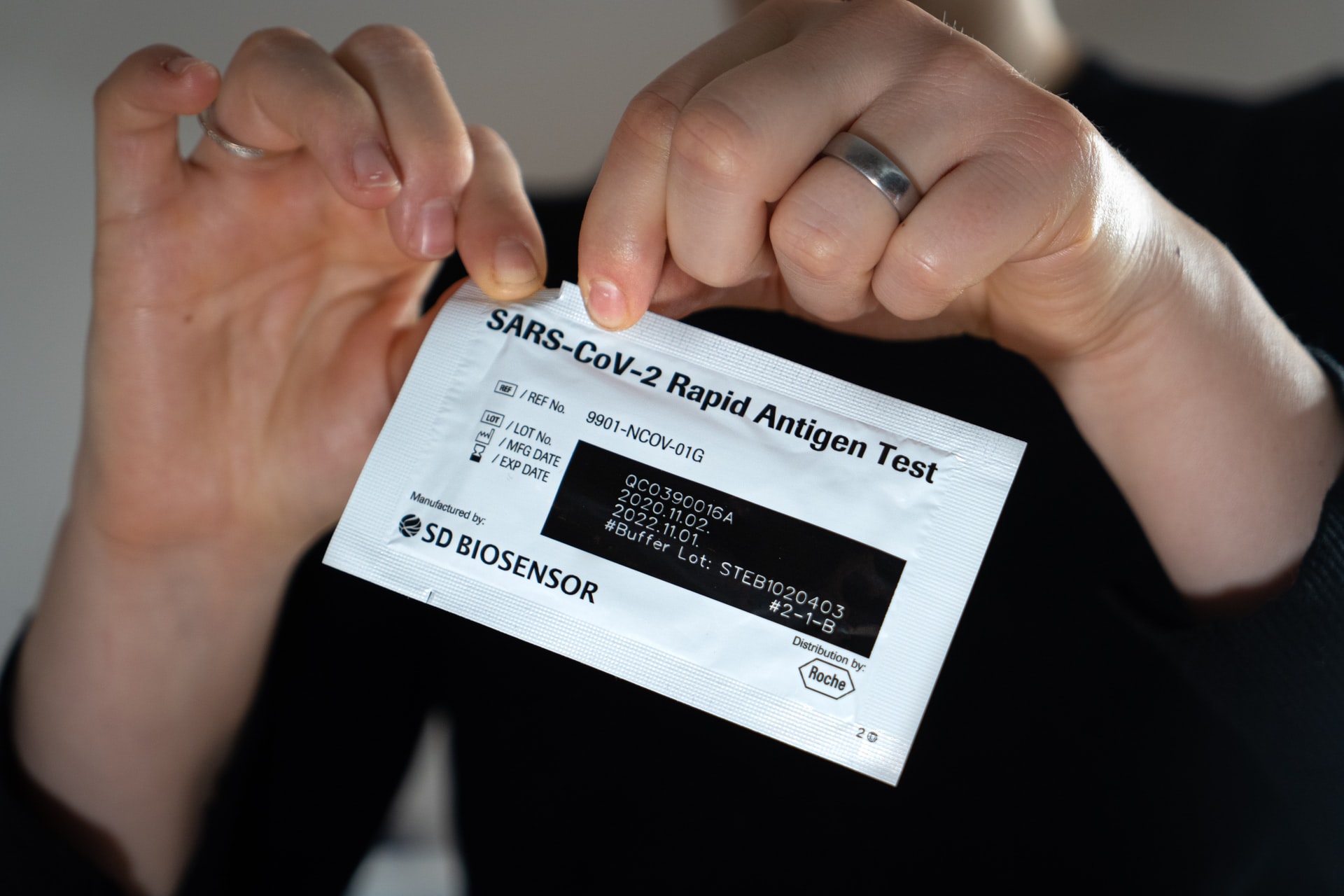Picture of a woman opening a COVID-19 test kit.