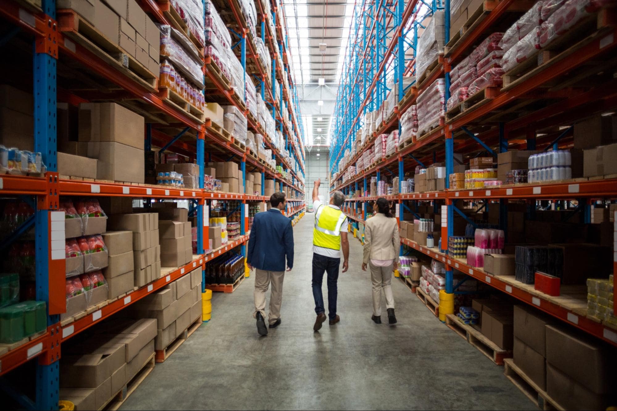 A picture of three people walking in a warehouse.