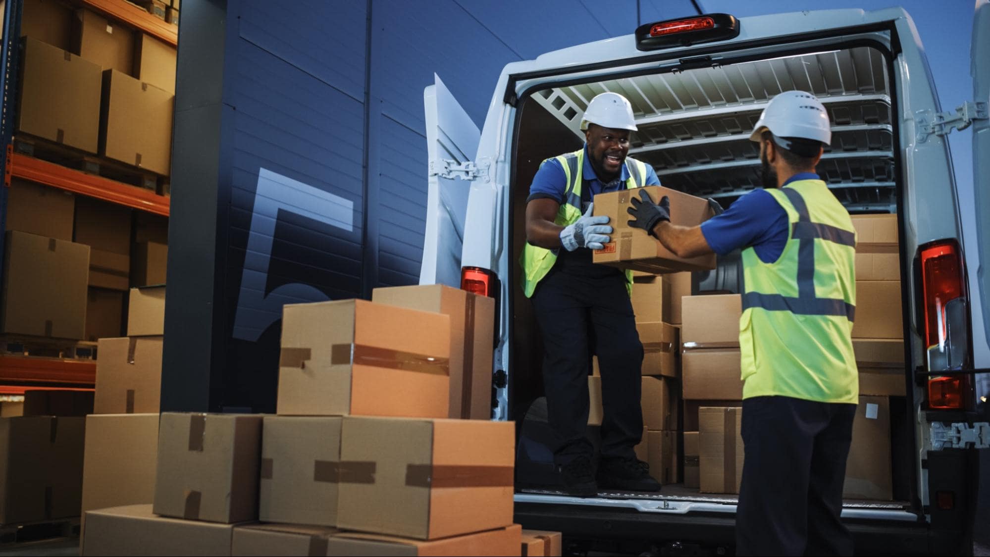 Delivery workers unloading boxes in front if a warehouse docking area.
