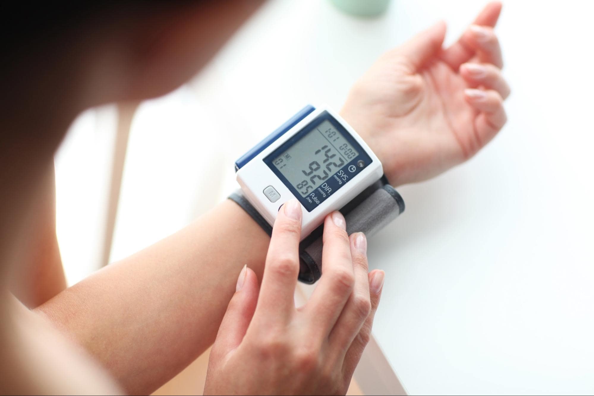A woman adjusting a portable health monitor on her wrist.