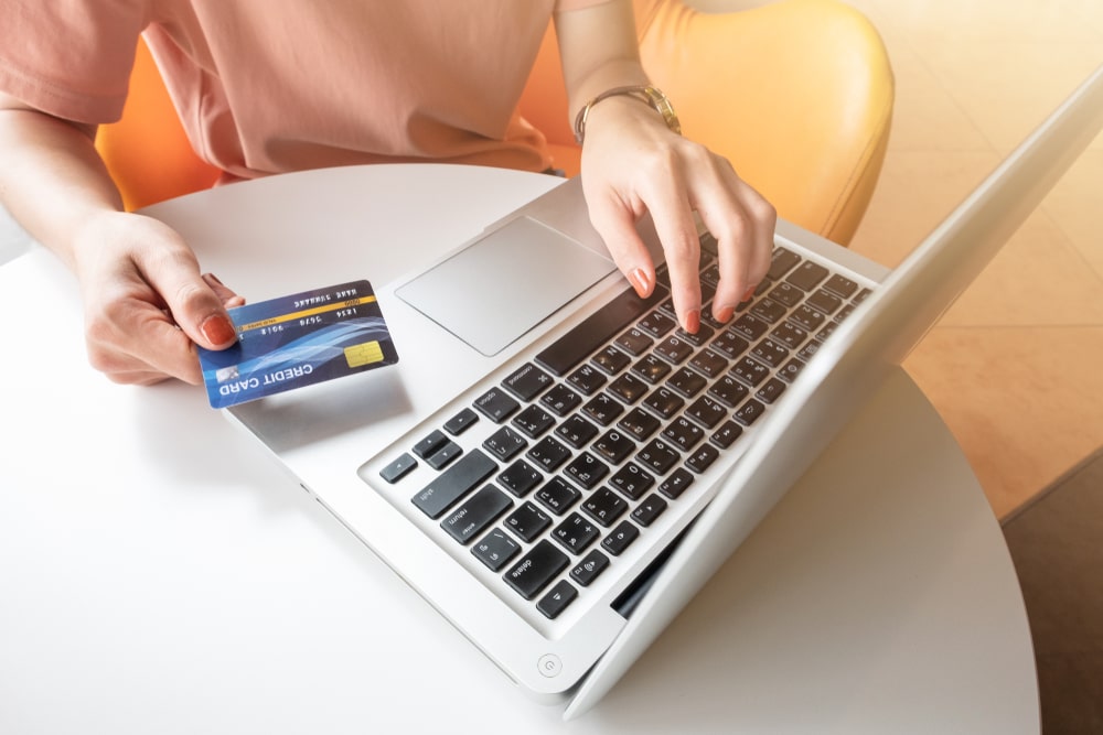 A woman looks the best 3PL partners for eCommerce online. She's on her laptop and holding a credit card.
