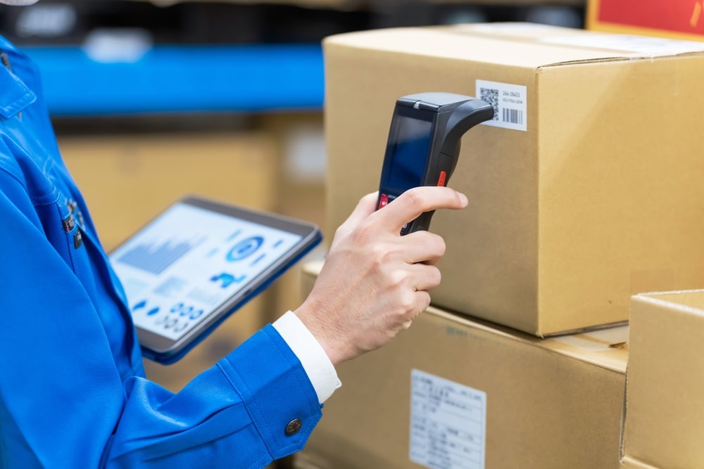 A 3PL eCommerce fulfillment partner employee scans a package on the warehouse floor. 
