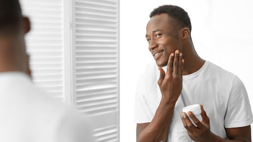 A man applying skin care moisturizing cream to his face. 