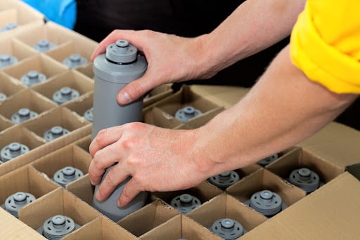 A fulfillment employee filling a box with water filters separated by corrugated inserts.