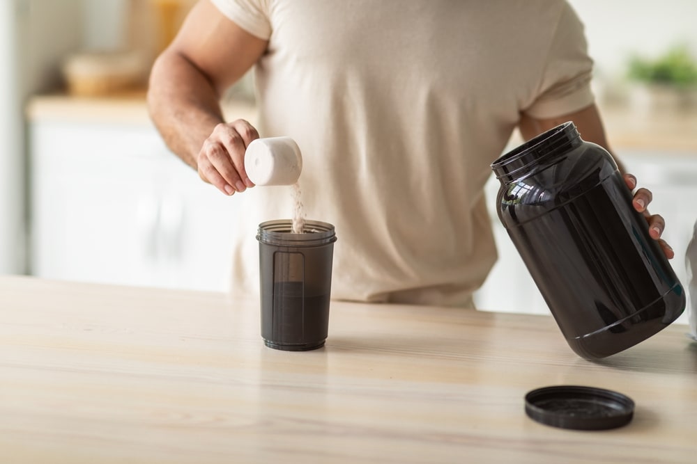a man dumping protein powder into his shaker bottle.